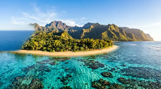 Vue panoramique de La Réunion montrant le contraste entre les lagons turquoise et les montagnes verdoyantes sous un ciel bleu