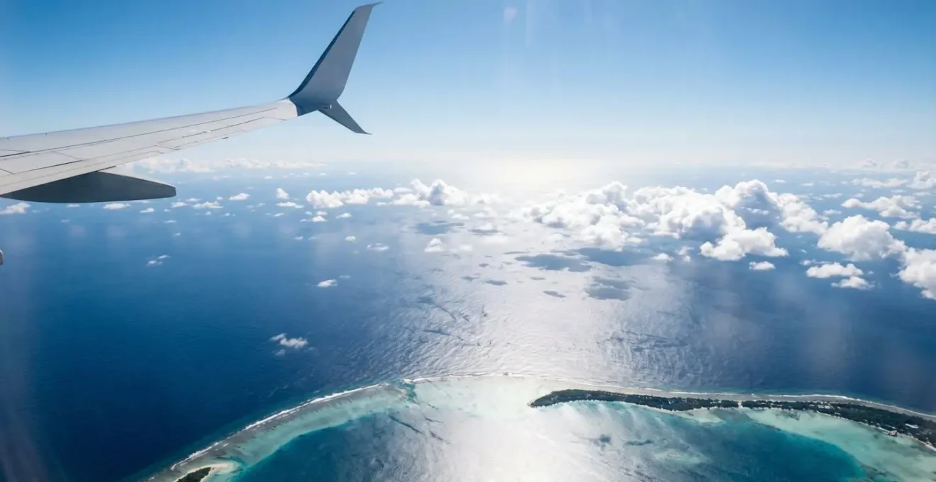 Vue aérienne d'un avion survolant l'océan Indien avec une île tropicale visible en contrebas