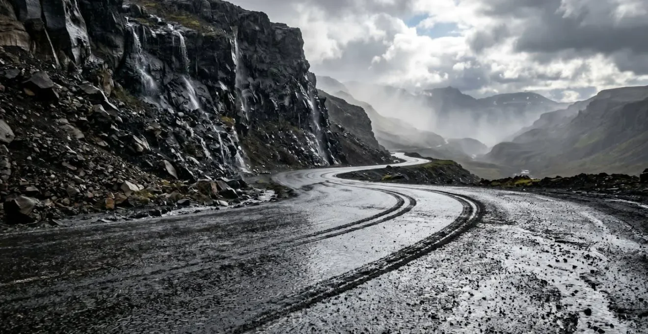 Route de montagne mouillée avec virages serrés et paroi rocheuse instable